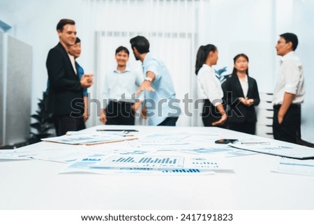 Business intelligence and analyzed financial data visualized on papers with blur background of analyst team utilizing BI Fintech in meeting room for business insight and marketing planning. Prudent