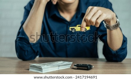 Closeup hand giving a car key and money for loan credit financial and rental. car loan concept, trade car for cash concept, finance concept. Buying or selling new or used vehicle. Car keys on table.