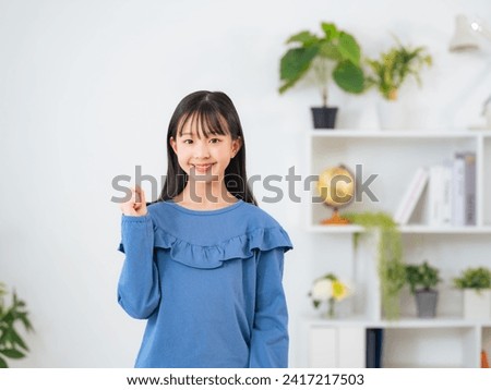 Asian little girl showing fist pump in room. Royalty-Free Stock Photo #2417217503