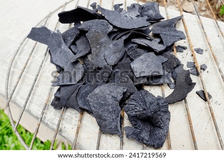 Charcoal flakes made from coconut shells are placed on the cement floor.