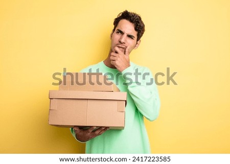 young handsome man thinking, feeling doubtful and confused. package boxes