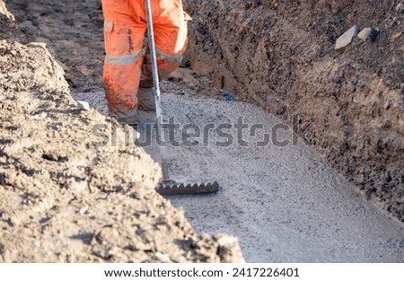 Concrete cast-in-place work. Builder leveling wet concrete. Concrete works on building construction site Royalty-Free Stock Photo #2417226401