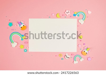 Blank white card on pastel pink background with frame of cute kawaii air plasticine handmade cartoon animals, stars, rainbows. Empty photo frames, baby's photo book, scrapbooking design template