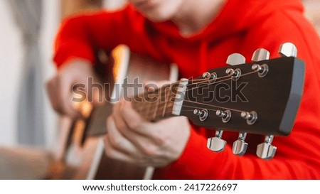 Guitar tuning. Music hobby. Song performance. Man professional artist hands adjusting pegs and gears on string acoustic instrument headstock indoors. Royalty-Free Stock Photo #2417226697
