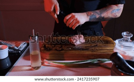 The chef sprinkles a piece of raw meat with pepper. Working environment on the kitchen table.
