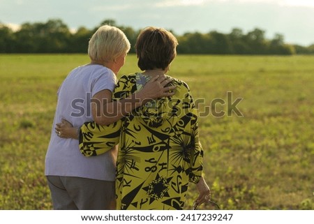 An affectionate shoulder-clasp between the women tells a story of shared histories and unfading camaraderie. Royalty-Free Stock Photo #2417239247
