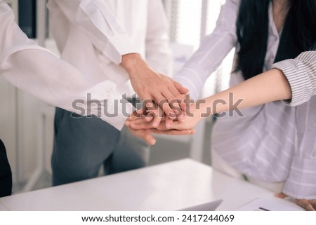 Close up of co- worker put hand in middle together at office with copy space.