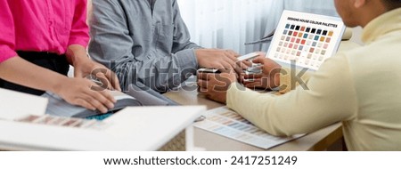 Professional architect presents color selection by using laptop displayed the color while female interior designer selects the curtain material. Creative working and teamwork concept. Variegated.
