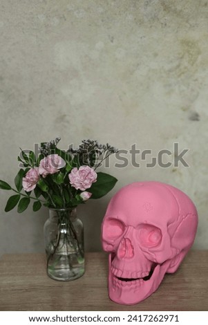 Pink skull and flowers in vase on wooden table, stock photo