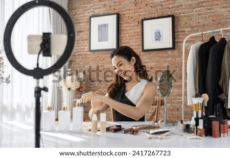Asian Woman influencer shoot live streaming vlog video review makeup uttermost social media or blog. Happy young girl with cosmetics studio lighting for marketing recording session broadcasting online Royalty-Free Stock Photo #2417267723