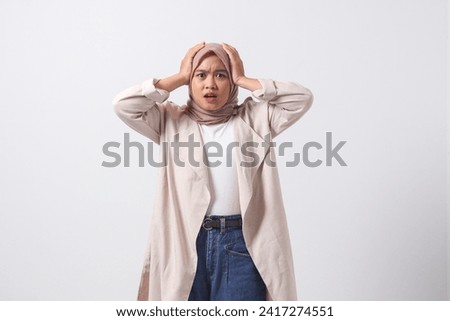 Portrait of frightened Asian hijab woman in casual suit holding head, showing surprised and scared expression. Isolated image on white background Royalty-Free Stock Photo #2417274551