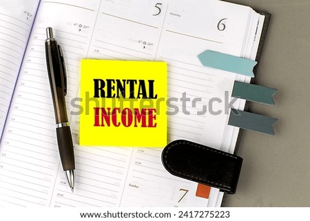RENTAL INCOME word on yellow sticky with office tools on daily planner