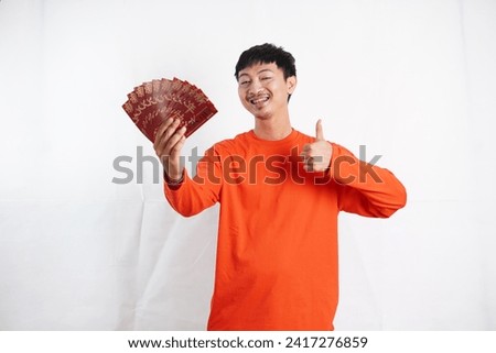 Happy Chinese new year. Asian man holding red packet monetary gift isolated on white background. Show good luck, greetings, and congratulations. funny face
