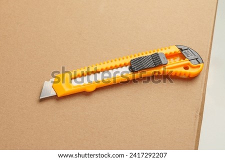 Box cutter on a parcel cardboard box close up. Retractable utility knife Royalty-Free Stock Photo #2417292207