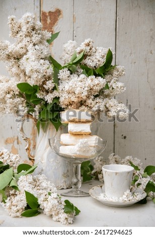 spring still life, a stack of waffle ice cream in a bowl and on a saucer, with a bouquet of white lilacs in an antique ceramic bowl, a cup of aromatic coffee, high quality photo