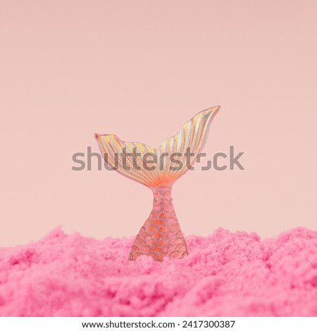 Creative trendy layout made with mermaid diving into pink sand against peachy pink background. Minimal summer concept. Fancy magical summer beach idea. Fantasy mermaid composition.
