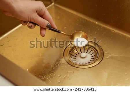 Cleaning kitchen sink with bakIng soda to keep sinks draining well and prevent clogs. Safe, effective, cheap, natural solution for clogged drains.	 Royalty-Free Stock Photo #2417306415