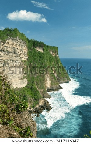 Photo view of Uluwatu, Bali is famous by surfers for its big waves. Pura Luhur Uluwatu temple is one of Bali's nine directional temples.