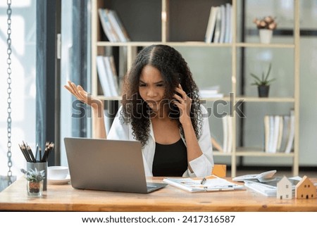 Black businesswoman talking seriously on the phone at the office table, Stressed out about work problems and mistakes.