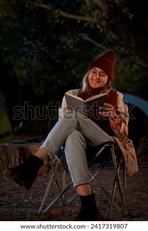 Serene caucasian woman at camping sitting outside during the night reading a book, disconnecting and enjoying the nature. Vertical photo with Copy space.