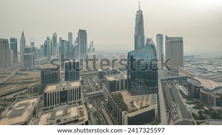 Futuristic Dubai Downtown and financial district skyline aerial night to day transition timelapse. Many illuminated towers and skyscrapers with morning fog before sunrise