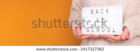 Banner with quote Back to school. Woman hold in hands lightbox with letters in front of yellow background. Place for text.