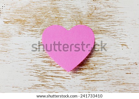 Valentines day card with sticky note in the shape of a heart on a wooden background, love message
