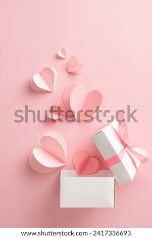 Romantic surprise for special lady. Overhead vertical shot of hearts soaring from gift box, portraying heartfelt emotions on soft pink backdrop. Space for your personalized message or advertisement Royalty-Free Stock Photo #2417336693