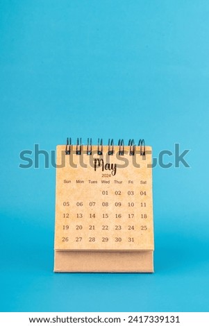 May 2024 white desk calendar on blue color background.