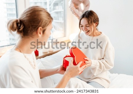 Smiling woman opening gift box. Happy attractive romantic couple celebration birthday sitting at home. Love, dating, Valentine's day concept
