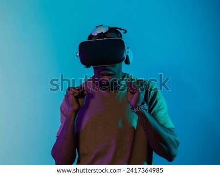 African American man immerses himself in a thrilling horror gaming experience using VR glasses, creating an isolated and intense atmosphere against a striking blue background