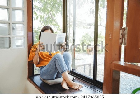 Close up teenage girl holding and reading book or magazine in reading room at home, copy space concept.