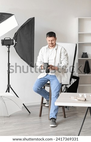 Male photographer with professional camera sitting in studio