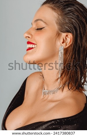 elegant woman in black velvet party dress with red lipstick and jewelry on her neck and earring, short hair thrown back