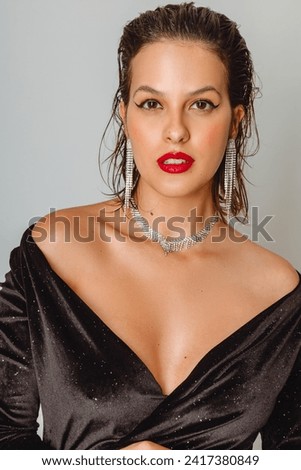 elegant woman in black velvet party dress with red lipstick and jewelry on her neck and earring, short hair thrown back