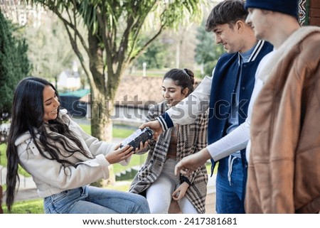 group of four young friends giving birthday present to their surprised latin friend outdoors