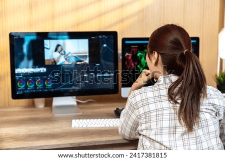 The back view of a young woman working on video editing at home