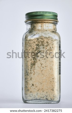 Jar of garlic, salt and herbs, Organic seasoning. close-up Glass container, closed green aluminum lid, gray background, recyclable packaging. Cooking courses concept, food storage, spices Royalty-Free Stock Photo #2417382275