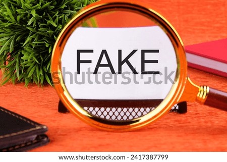 FAKE word written on a business card through a magnifying glass on an orange background