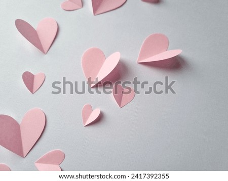 Pink paper hearts of different sizes on a light background. Delicate minimalistic holiday background. Holiday card for Valentine's Day