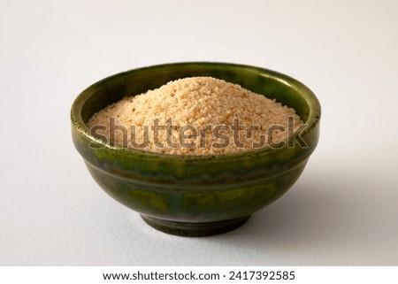  View of a green ceramic bowl filled with breadcrumbs on white background Royalty-Free Stock Photo #2417392585