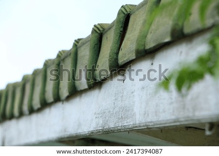 The arrangement of roof tiles on top of wooden planks, against a bright daytime sky.