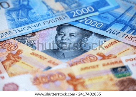 Chinese yuan banknote surrounded by russian rubles. Concept of economic cooperation between the China  and Russia, trading and support Royalty-Free Stock Photo #2417402855
