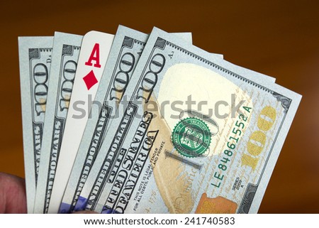 Hand holding four new one hundred dollar bills and an As of diamonds card, like if it was a poker hand.