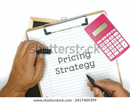 The word PRICING STRATEGY is written at writing paper with hand holding pen and calculator isolated white background. 