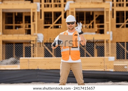 Man Contractor holds piece of empty cardboard sign in his hands. a male construction worker in a helmet stands in a construction zone with empty cardboard. Construction Worker on Duty
