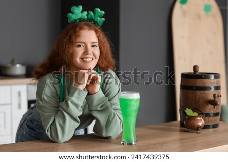 Young woman with beer in kitchen. St. Patrick's Day celebration