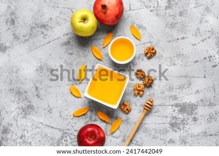 Bowls of sweet honey with walnut, pomegranate and apples on grey background