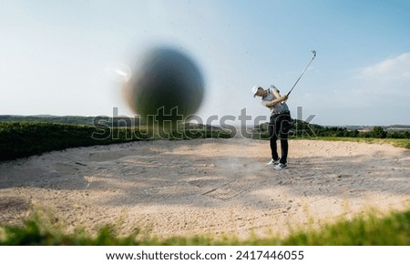 green, golf, ball, club, course, golfer, grass, sport, golfing, fairway. bunker shot, pro golf player hitting golf ball out of a deep sand trap. and ball is going straight coming to impact camera. Royalty-Free Stock Photo #2417446055