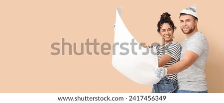 Happy young couple planning repair on beige background. Banner for design